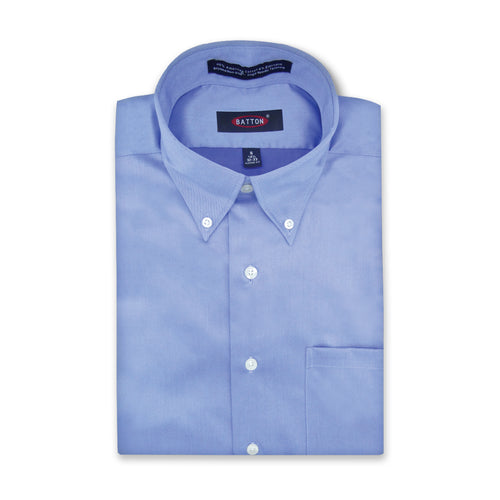 Folded light blue dress shirt with a brand label on a white background